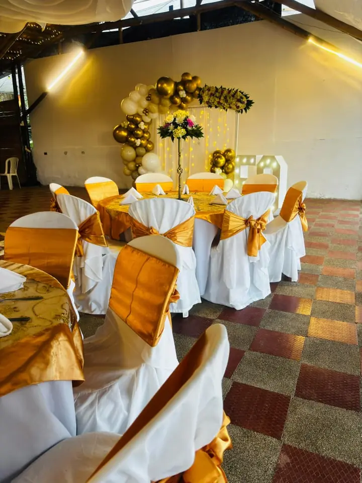 Sillas con lazos dorados y arco de globos en el salón