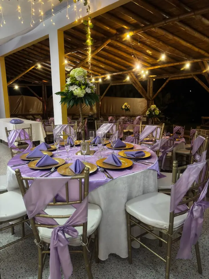 Montaje de evento con mesas lila bajo techo de madera