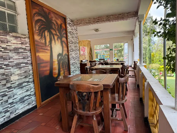 Terraza del restaurante con mural de palmeras